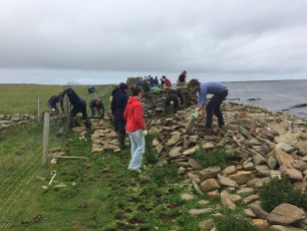 The team start building a new section of dyke wall on firmer ground, a few metres inland from the original wall that was destroyed in winter storms